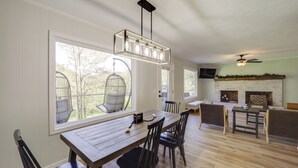 A dining area with a wooden table and chairs, a hanging light fixture, and a fireplace in the background. - 24 Private Acres: Trails/hot Tub Near Blowing Rock (Lenoir)
