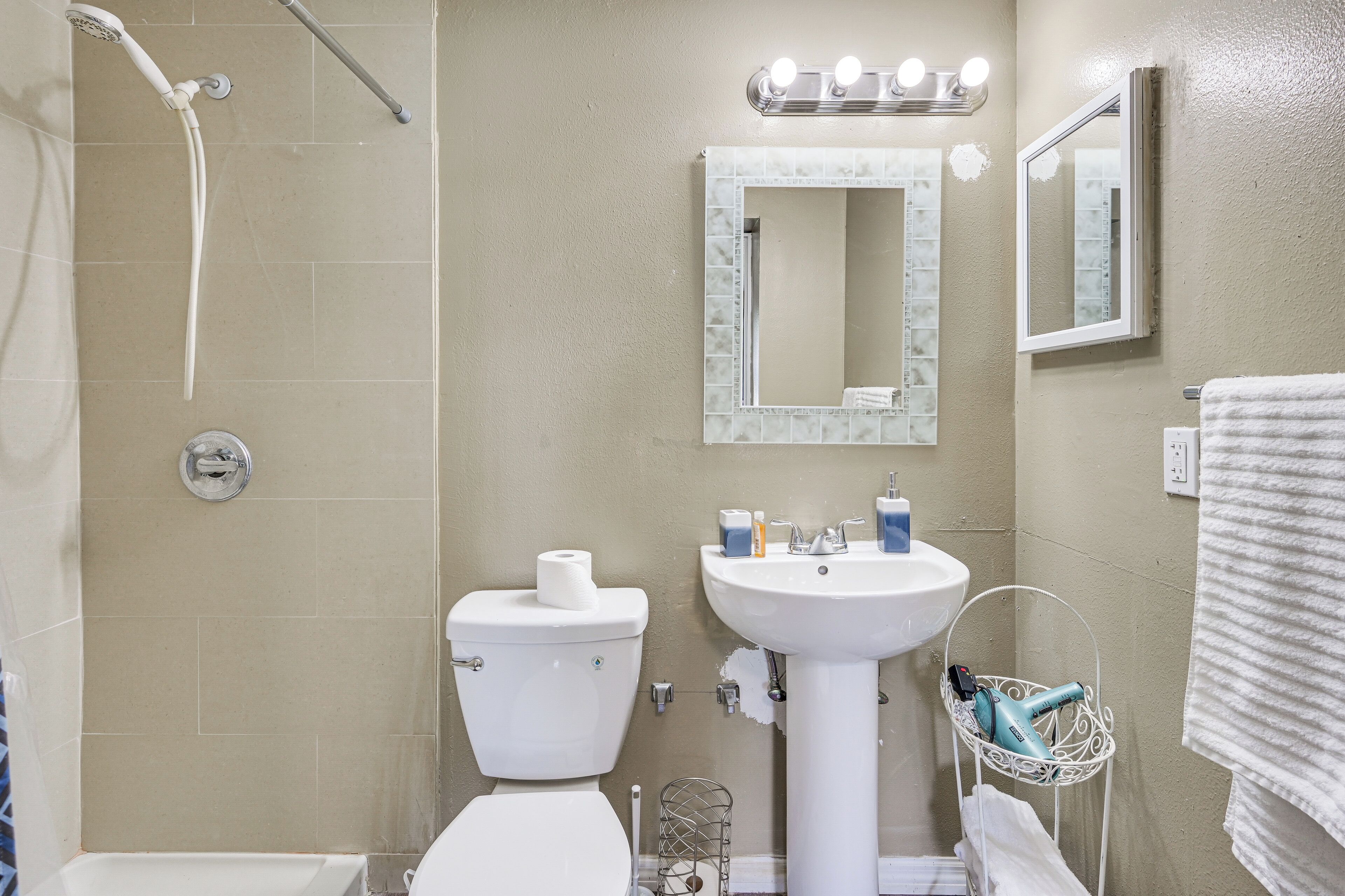 A bathroom with a shower, toilet, sink, and a towel rack.