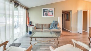 Ein Wohnzimmer mit einem Couchtisch aus Glas, einem beigefarbenen Sofa und einem gerahmten Bild an der Wand.