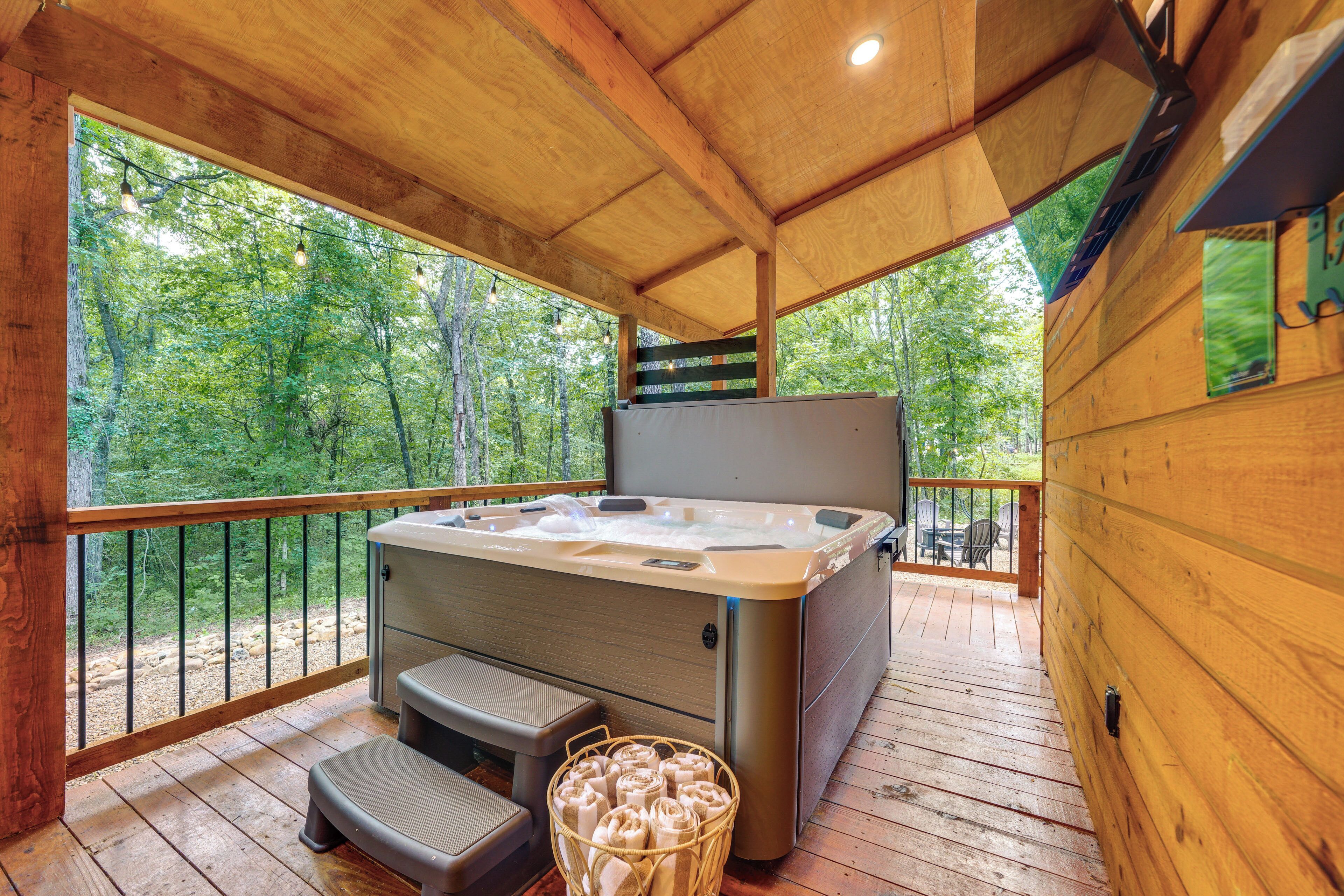 Une terrasse en bois avec un jacuzzi, un banc et un panier rempli de serviettes.