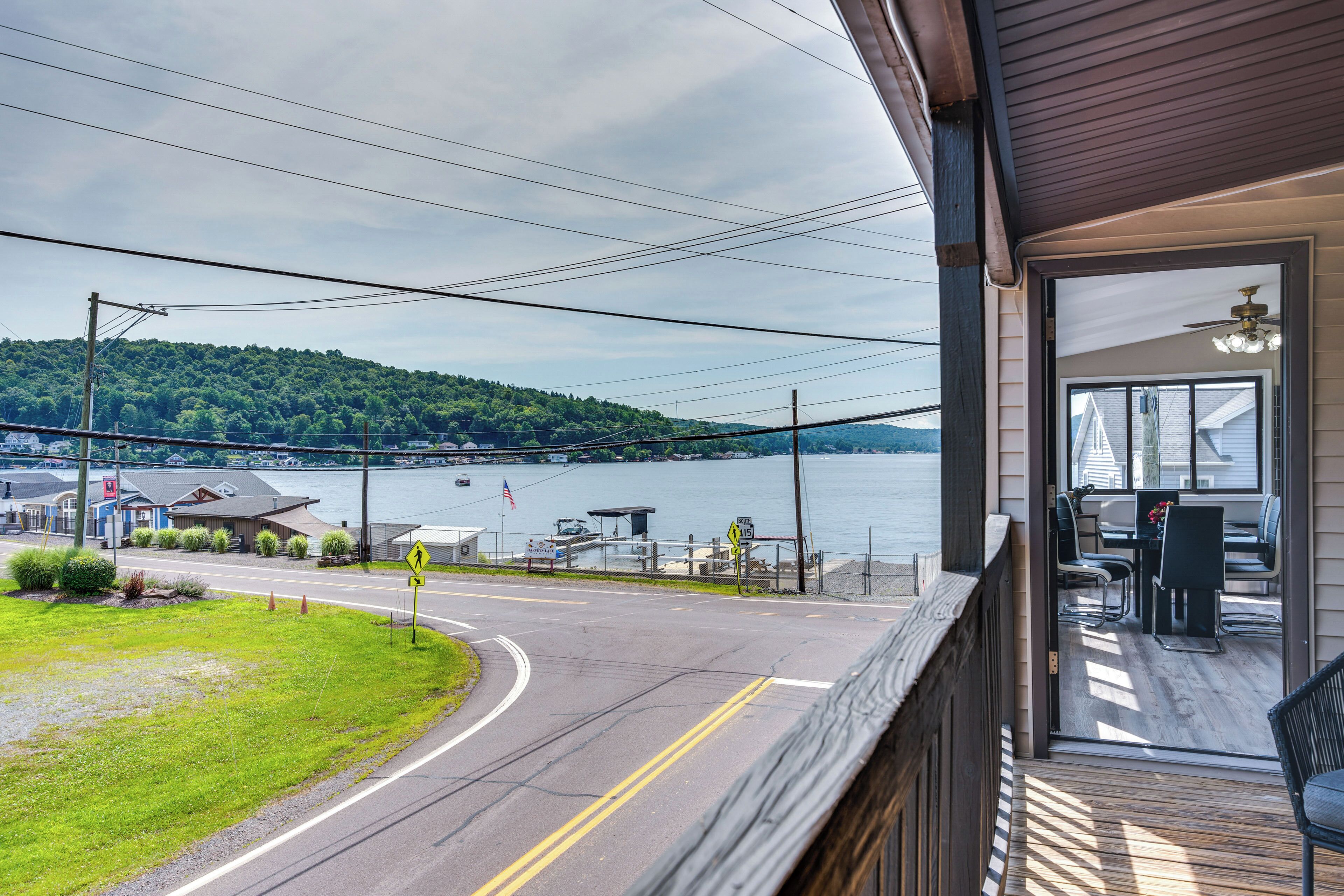 A view from a balcony overlooking a lake with a dock, a restaurant, and a road with a pedestrian crossing.