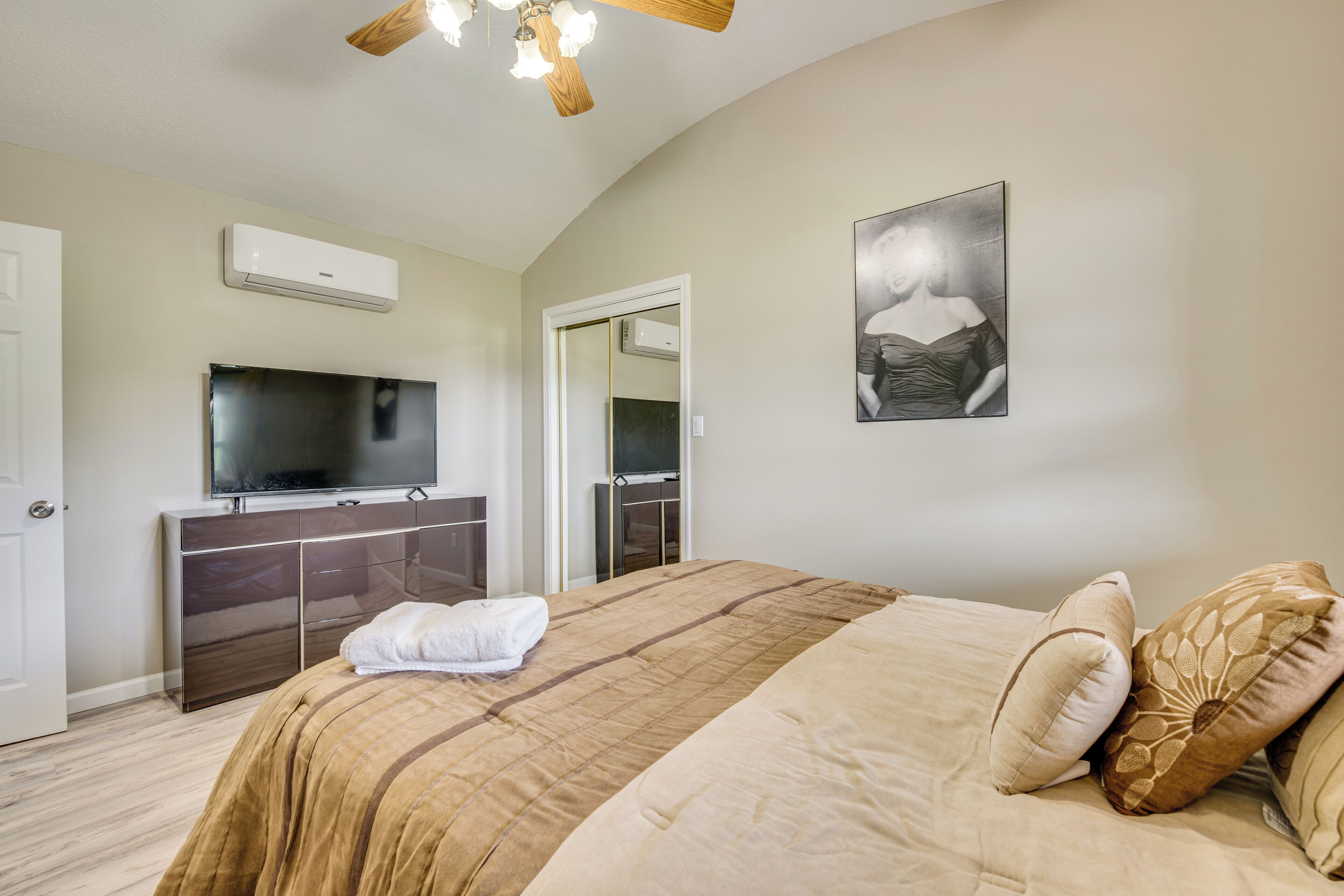 Une chambre dotée d’un grand lit, d’un téléviseur à écran plat, d  ’une armoire et d’un ventilateur de plafond.