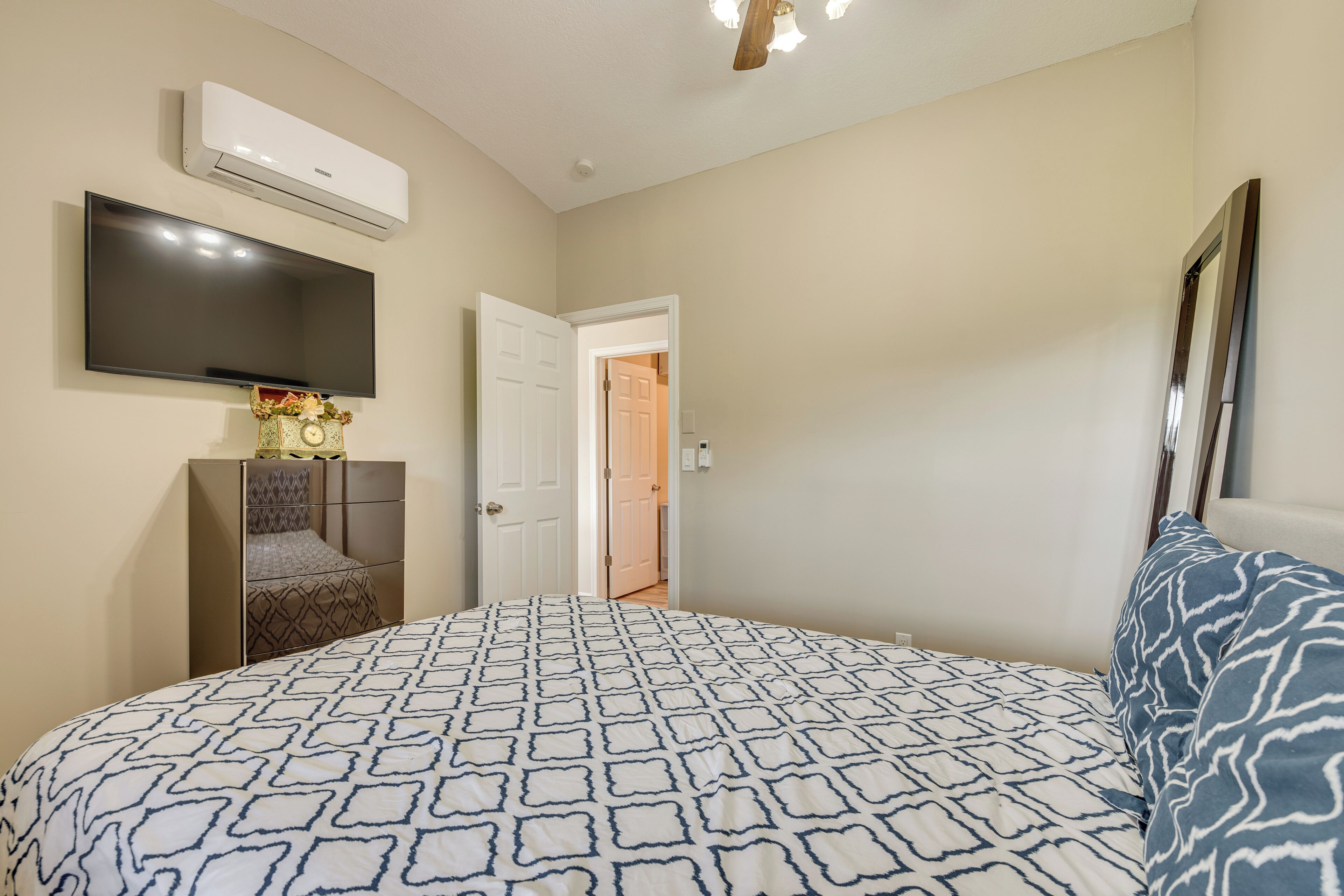 A bedroom with a bed, a TV, an air conditioner, and a wardrobe.
