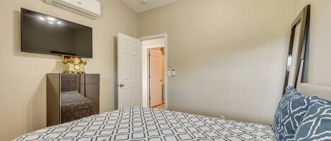 A bedroom with a bed, a TV, an air conditioner, and a wardrobe.