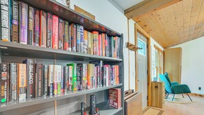 Una habitación con una estantería llena de libros, un sillón mecedor y suelo de madera.