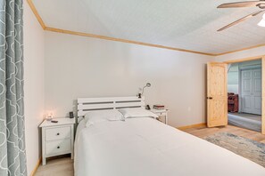 A bedroom with a bed, nightstands, a bedside table, a ceiling fan, and an open door leading to another room. - 5 Mi to Cave Run Lake: Wellington Cabin w/ Deck! (Wellington)
