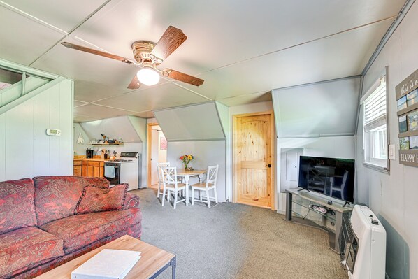 A compact living space with a sofa, a dining table with chairs, a television, and a ceiling fan. - 5 Mi to Cave Run Lake: Wellington Cabin w/ Deck! (Wellington)