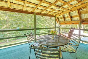 A covered outdoor seating area with a round table and chairs, a view of a forest, and a metal ceiling structure. - 5 Mi to Cave Run Lake: Wellington Cabin w/ Deck! (Wellington)