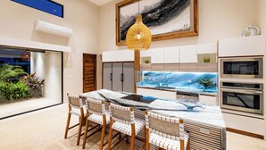 A modern kitchen with a marble countertop, built-in oven, and a large window overlooking a garden. - Modern villa at exclusive Hacienda Pinilla 5min from beach/golf & beach club (Tamarindo)