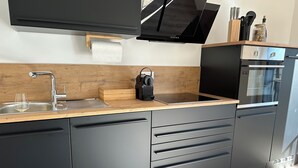 Une cuisine moderne dotée d’un plan de travail en bois, d’appareils électroménagers en acier inoxydable et d’un four encastré.