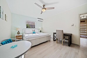 A bedroom with a bed, a desk, a chair, a table, and a ceiling fan. - Private Pool & Patio Haven, 3BR House near Beach (Noord)
