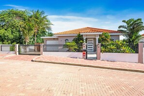 A residential property with a gated entrance, a tiled roof, and a paved driveway. - Private Pool & Patio Haven, 3BR House near Beach (Noord)