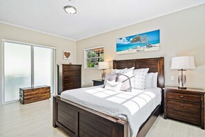 A bedroom with a large bed, two bedside tables, a dresser, and a sliding glass door leading to a balcony. - Private Pool & Patio Haven, 3BR House near Beach (Noord)