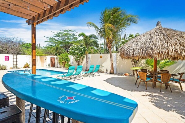 A pool area with lounge chairs and a thatched umbrella.