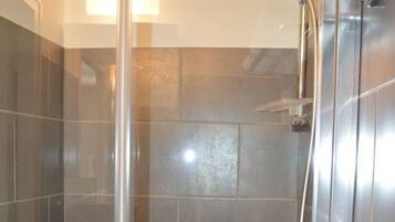 A modern shower enclosure with a glass door, a handheld showerhead, and a towel rack.
