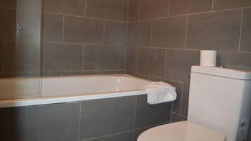 A bathroom with a bathtub, toilet, and tiled walls.