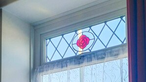 A window with a decorative metal grille and a rose-shaped stained glass window. - Bramble Cottage Rhondda Valley by STAE-Homes (Tylorstown)