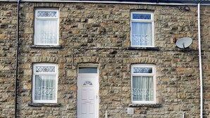 A stone building with a central entrance, two windows on each side, and a satellite dish on the roof. - Bramble Cottage Rhondda Valley by STAE-Homes (Tylorstown)