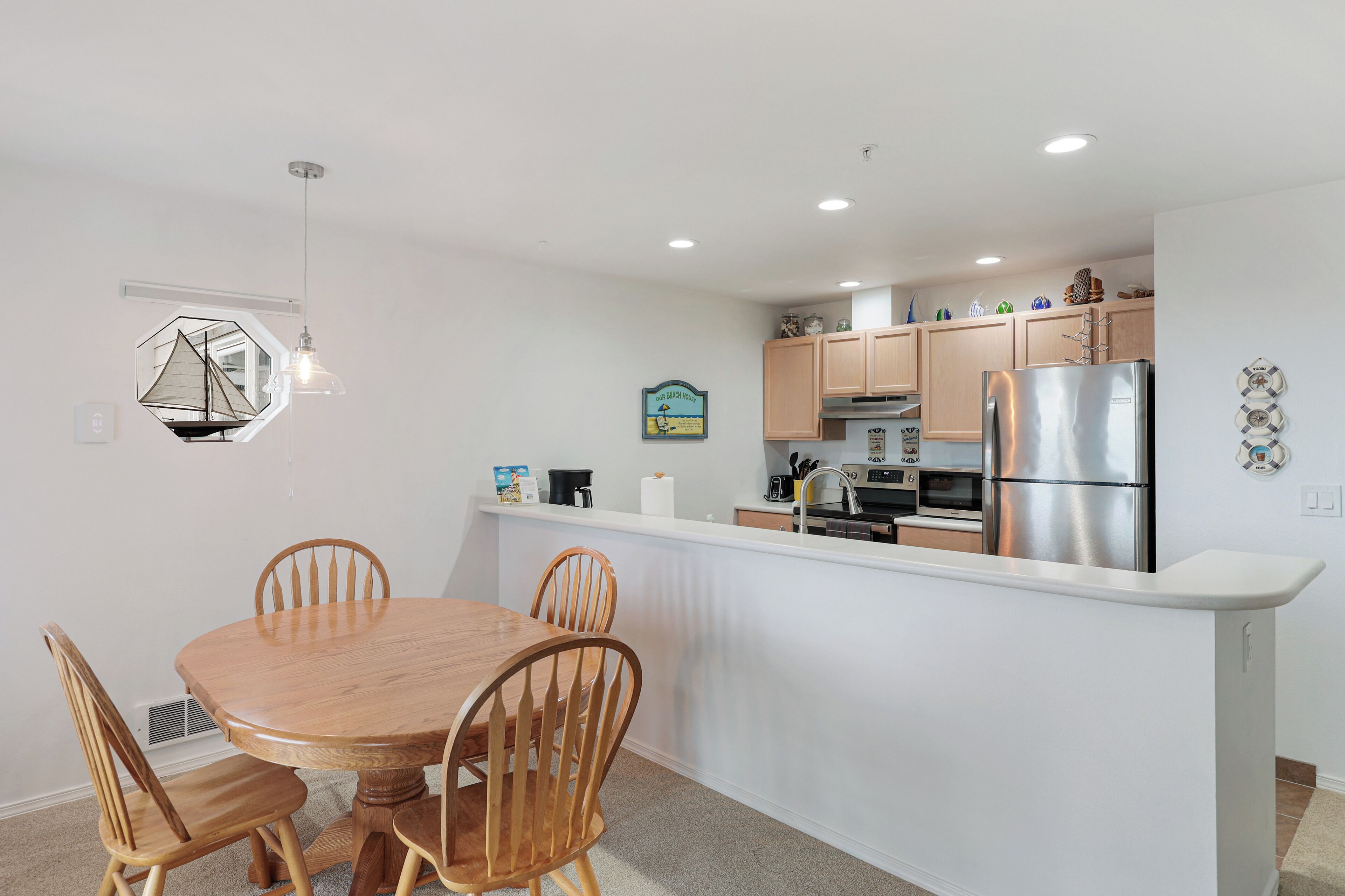 A modern kitchen with a central island, wooden chairs, and a pendant light.