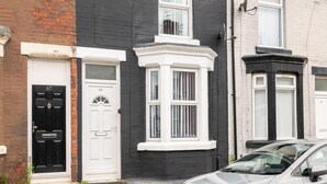 A row of terraced houses with distinct front doors and bay windows. - Host & Stay | Bardsay Road (Liverpool)