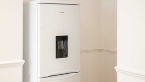 A white refrigerator with a water dispenser, located in a room with white walls and a simple, clean design. - Host & Stay | Bardsay Road (Liverpool)