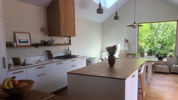 A modern kitchen with a central island, wooden cabinets, and pendant lighting.
