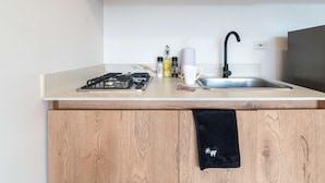 A kitchen with a gas stove, a sink, and a black towel hanging on the cabinet.