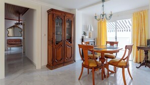 Un comedor con una mesa y sillas de madera, una araña y un mueble de madera grande.