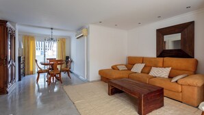 Una sala de estar con sofá, mesa de centro y comedor con sillas y una mesa.