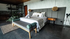 A modern bedroom with a large bed, a wooden bench, a small table, and a tripod. - Casita 2 Beautiful Cabin - Stunning View (Filandia)