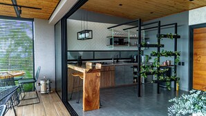 A modern kitchen with a wooden island, bar stools, and a glass partition. - Casita 2 Beautiful Cabin - Stunning View (Filandia)