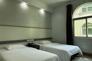 A hotel room with two beds, a nightstand, a window with curtains, and a wall-mounted light fixture. - Wangfuzhou Holiday Villa Hotel (Taishan)