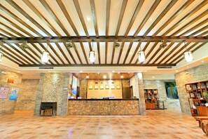A reception area with a stone wall, wooden reception desk, and a fireplace.