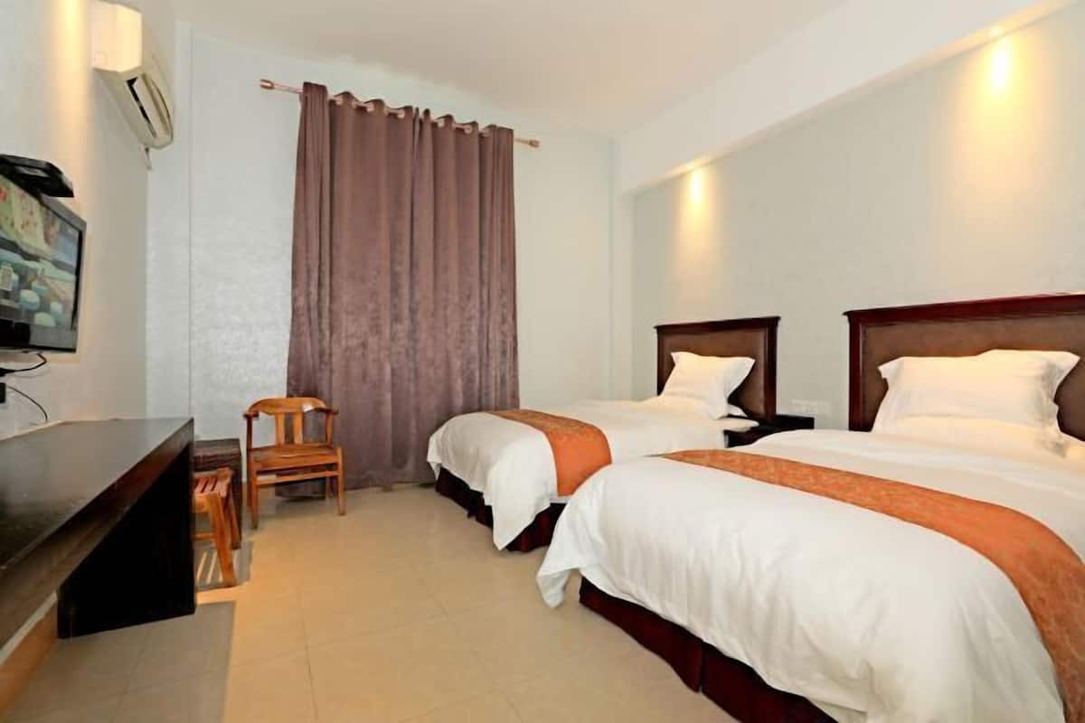 Une chambre d’hôtel avec deux lits, un bureau, une chaise et un téléviseur.