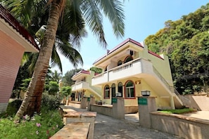A two-story building with a balcony, a staircase, and a pathway leading to the entrance.