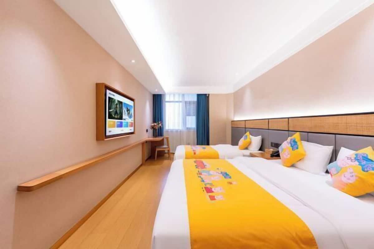 A hotel room with two beds, a desk, and a large window.
