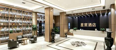 A hotel lobby with a reception desk, seating area, and bookshelves.