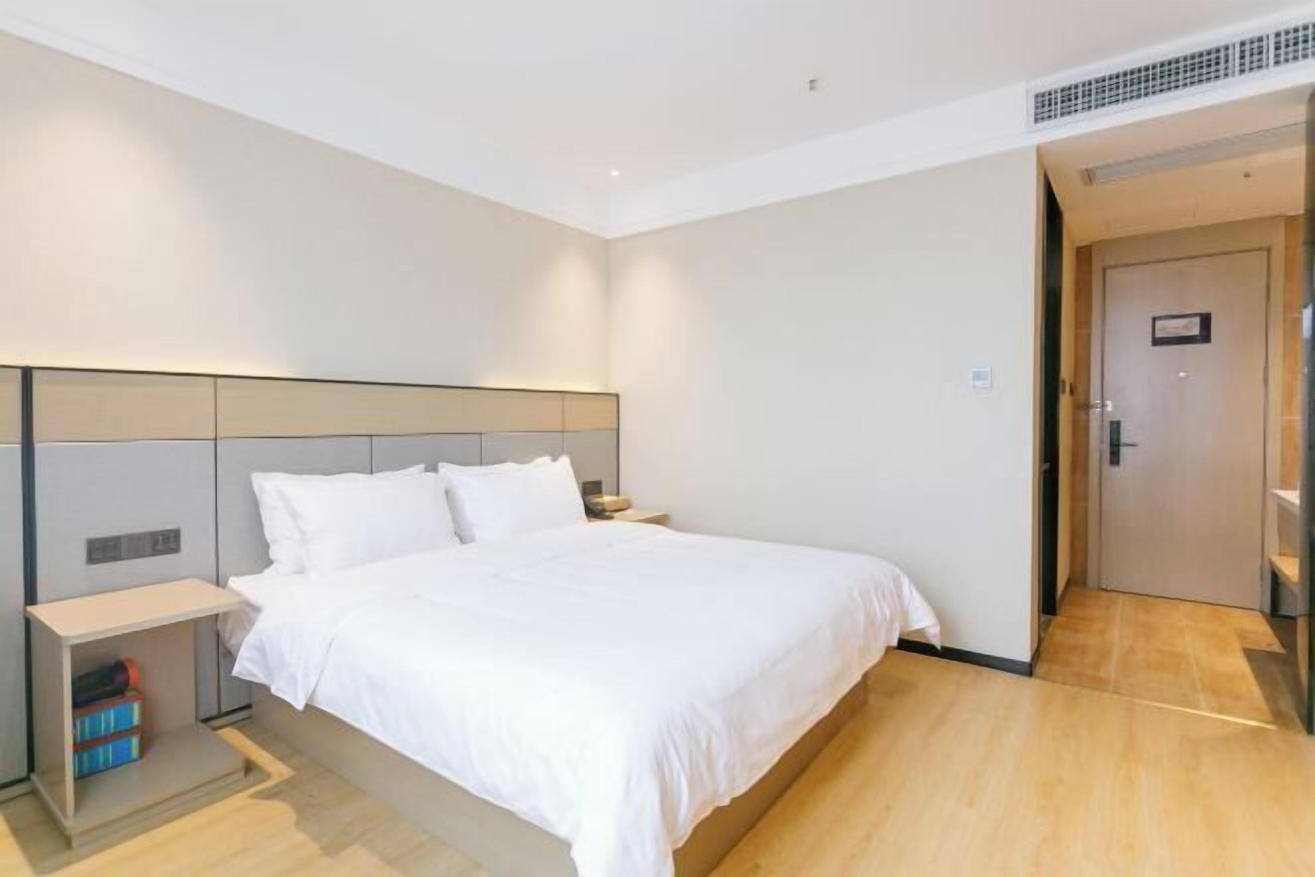 Ein modernes Hotelzimmer mit einem großen Bett, einem Nachttisch und einem Kleiderschrank.