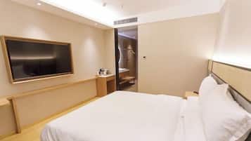 A hotel room with a bed, a TV mounted on the wall, a wooden nightstand, and a walk-in closet.