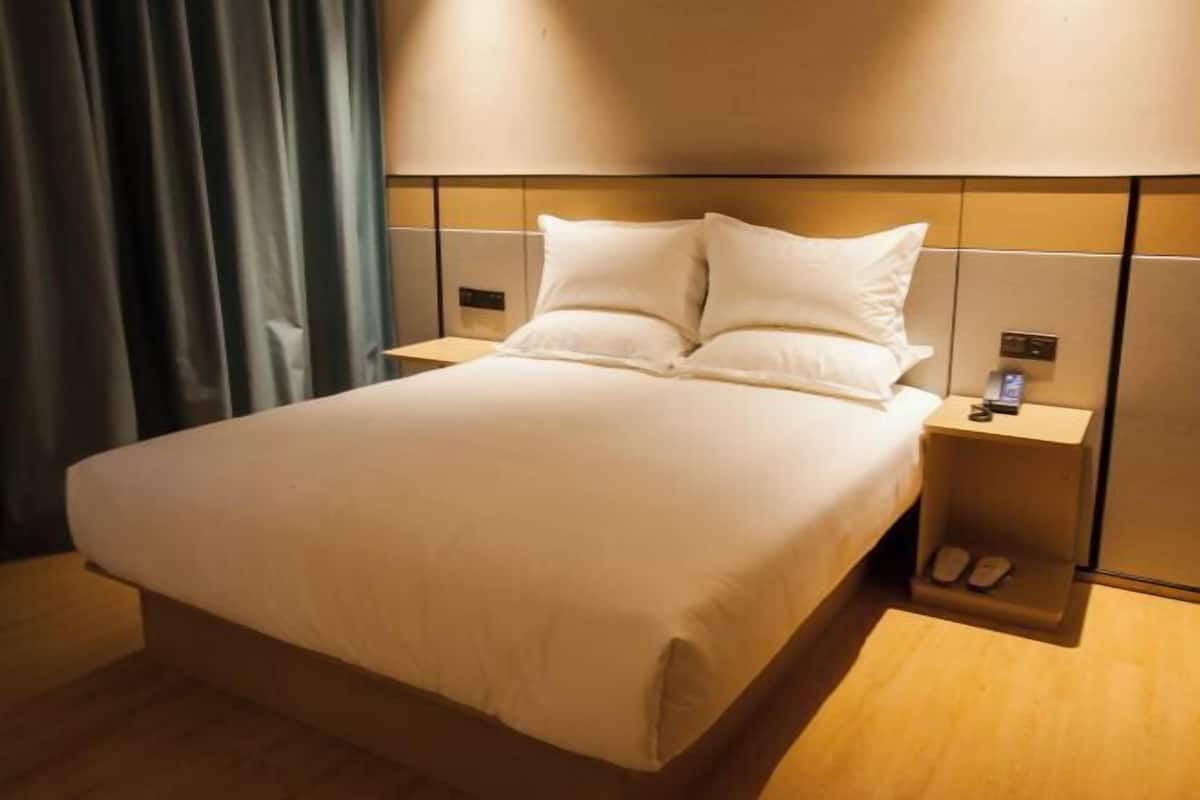 A hotel room with a bed, nightstands, and a shoe storage unit.