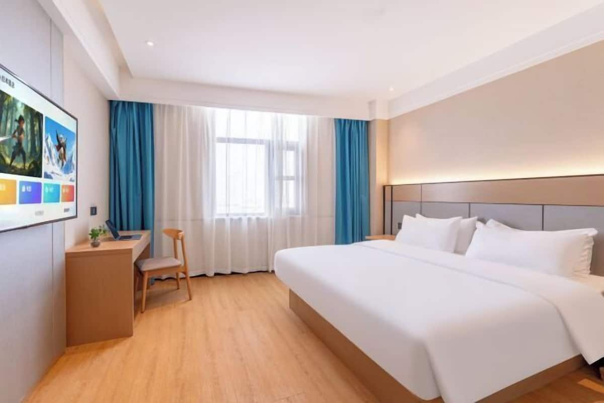 A hotel room with a large bed, a desk, and a chair.