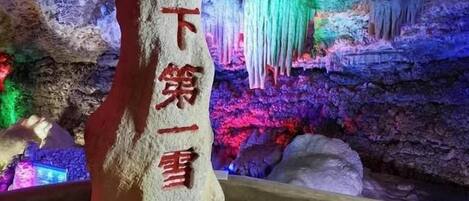 Un rocher orné de caractères chinois, entouré de formations rocheuses et illuminé de couleurs vives.