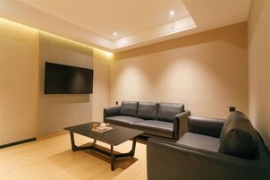 Una sala de estar moderna con un sofá, una mesa de centro y un televisor de pantalla plana montado en la pared.