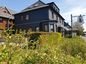 A two-story house with a dark blue exterior, multiple windows, and a covered porch area. - Siegmundsburger Haus Werraquelle here apartment "Rennweg" - ground floor, pet friendly (Siegmundsburg)