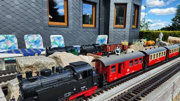 Un modellino di treno con una locomotiva nera, vagoni passeggeri rossi e una piccola statuetta.