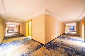 A hotel corridor with a carpeted floor, doors on both sides, and a blue window at the end. - Bai Yas Hotel (Zunyi Haier Avenue &Wuyue PIaza Branch) (Zunyi)