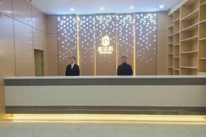 A reception desk with a modern design, featuring a logo and a patterned backdrop. - Bai Yas Hotel (Zunyi Haier Avenue &Wuyue PIaza Branch) (Zunyi)