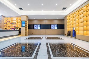 A hotel lobby with a reception desk, seating area, and a large wall with built-in shelves. - Bai Yas Hotel (Zunyi Haier Avenue &Wuyue PIaza Branch) (Zunyi)