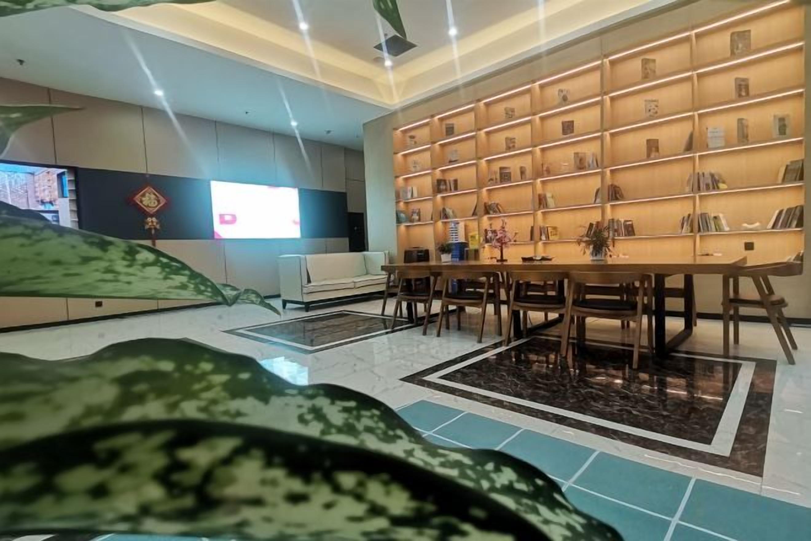 A modern hotel lobby with a large bookshelf, a reception desk, and a seating area.