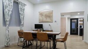 A dining area with a wooden table and six chairs, a flat-screen TV, and a world map on the wall.